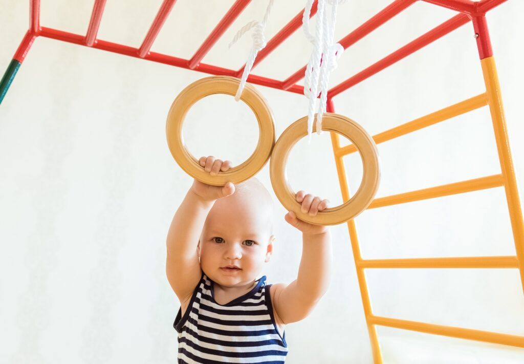 Child boy hanging on gymnastic rings at home