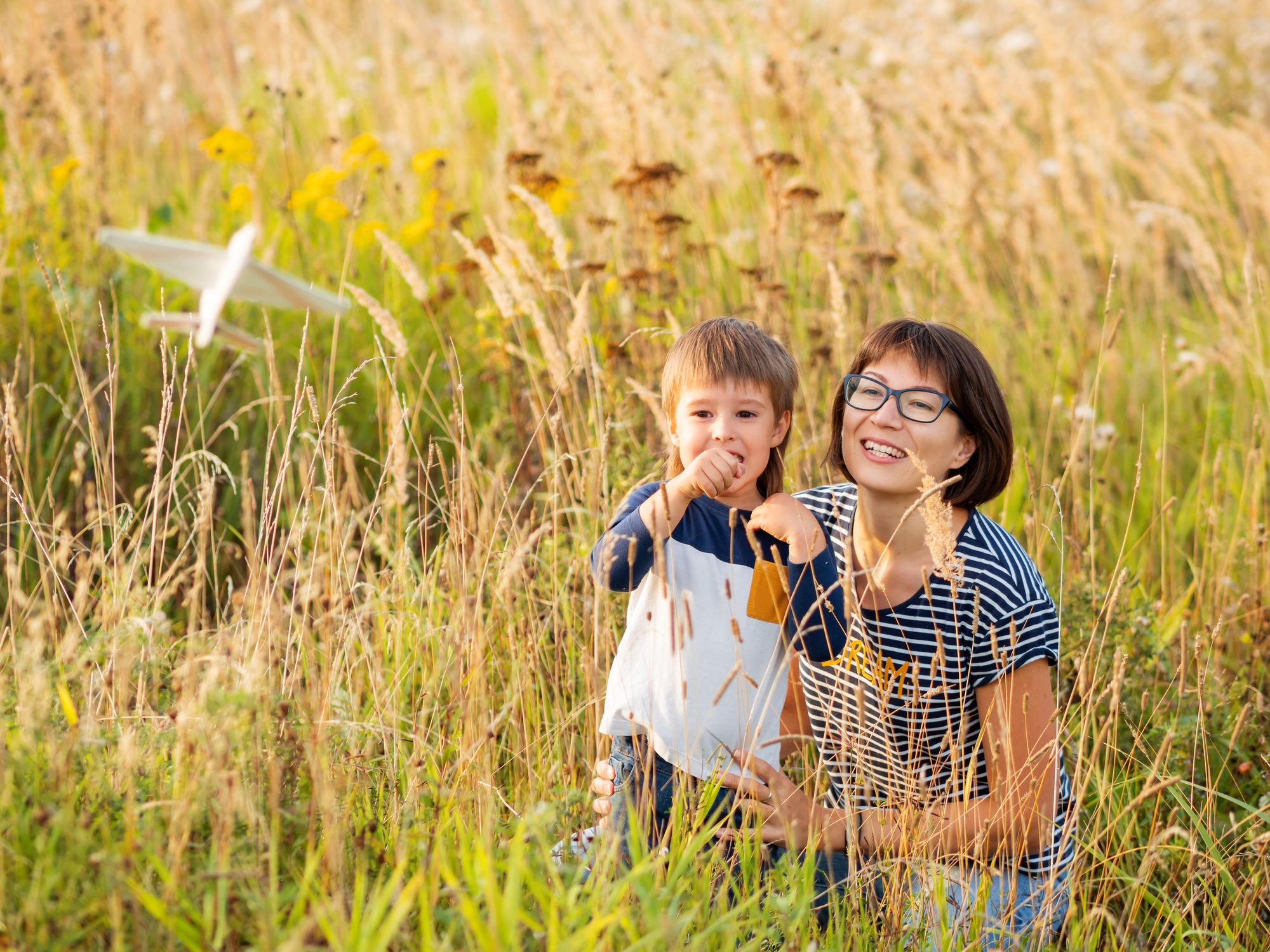 Cute boy and his mother play with toy air plane. Happy kid dreams to be a pilot. Mom with kid.